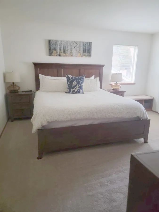 Bedroom with a white duvet and artwork above the headboard