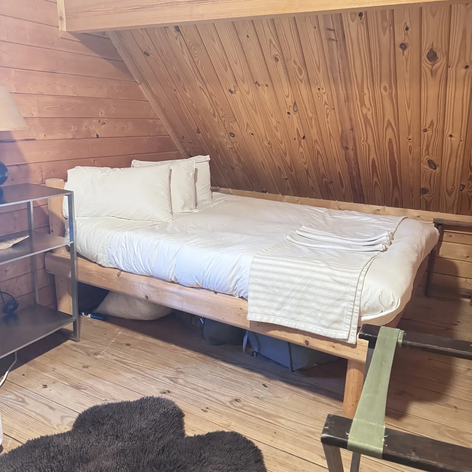 Made bed beneath a sloping wooden ceiling
