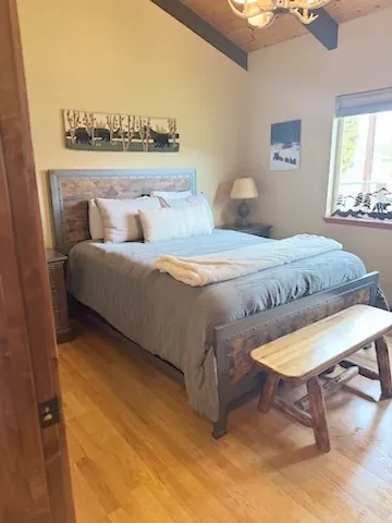 Bedroom with a wooden bench at the foot of the bed and a wood floor